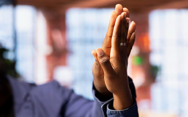 A raised hand in a meeting room